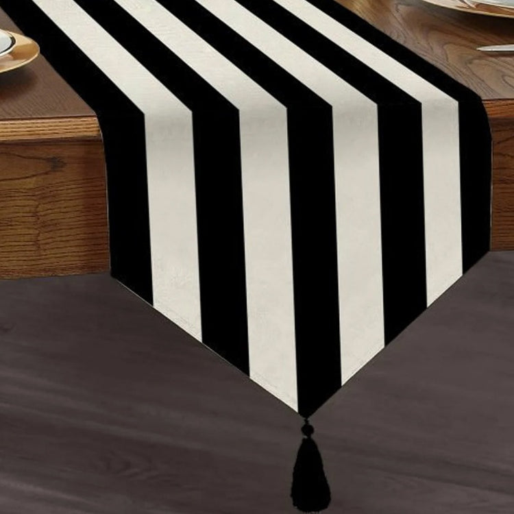 Table runner with broad black and white stripes and a tasselled end.