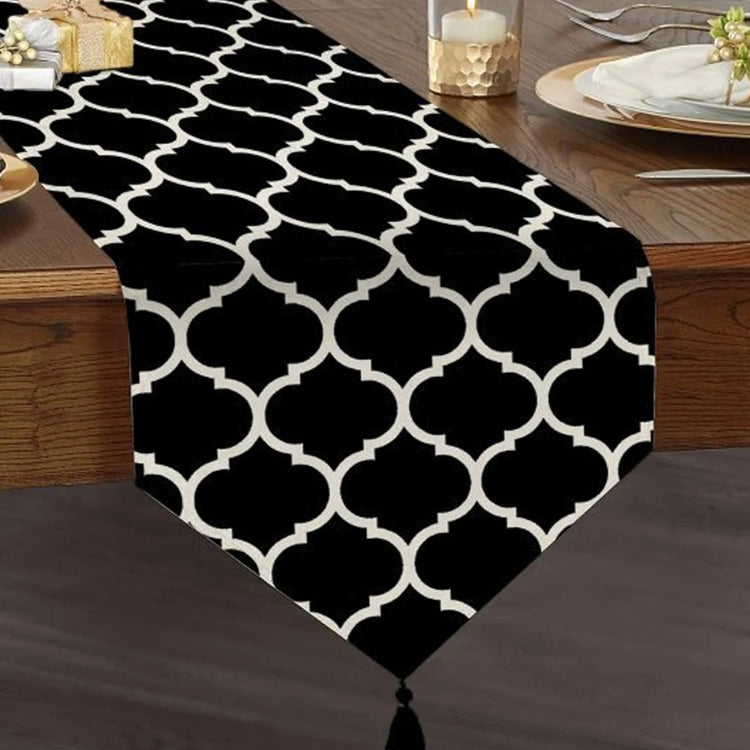 Black table runner with a white trellis pattern and a tasselled end.
