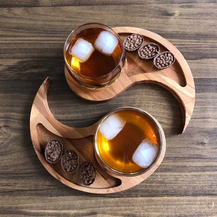 Two curved wood-tone trays holding glasses of iced drinks and small snacks