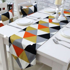 Table runner with multicoloured triangles displayed with matching patterned chair cushions.