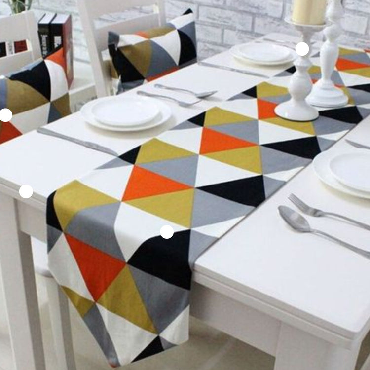 Table runner with multicoloured triangles displayed with matching patterned chair cushions.