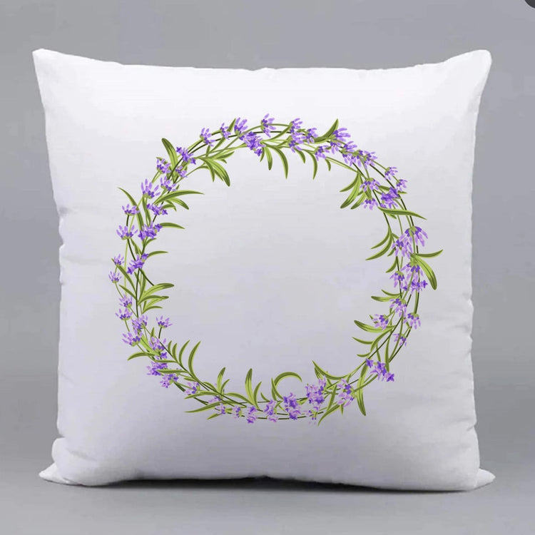 White cushion cover with a circular wreath of purple flowers and green leaves.