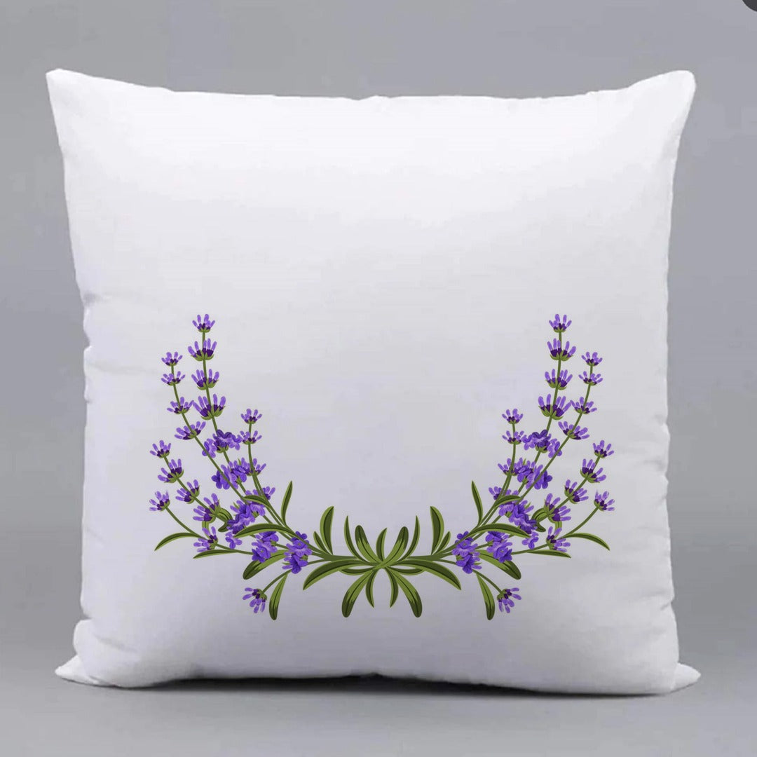 White cushion cover with a curved garland of purple flowers and green leaves.
