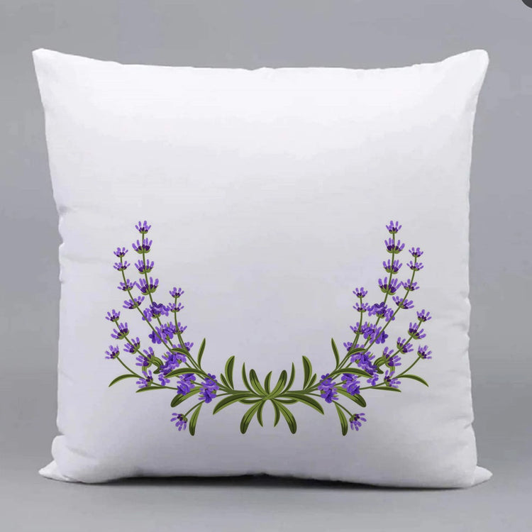 White cushion cover with a curved garland of purple flowers and green leaves.