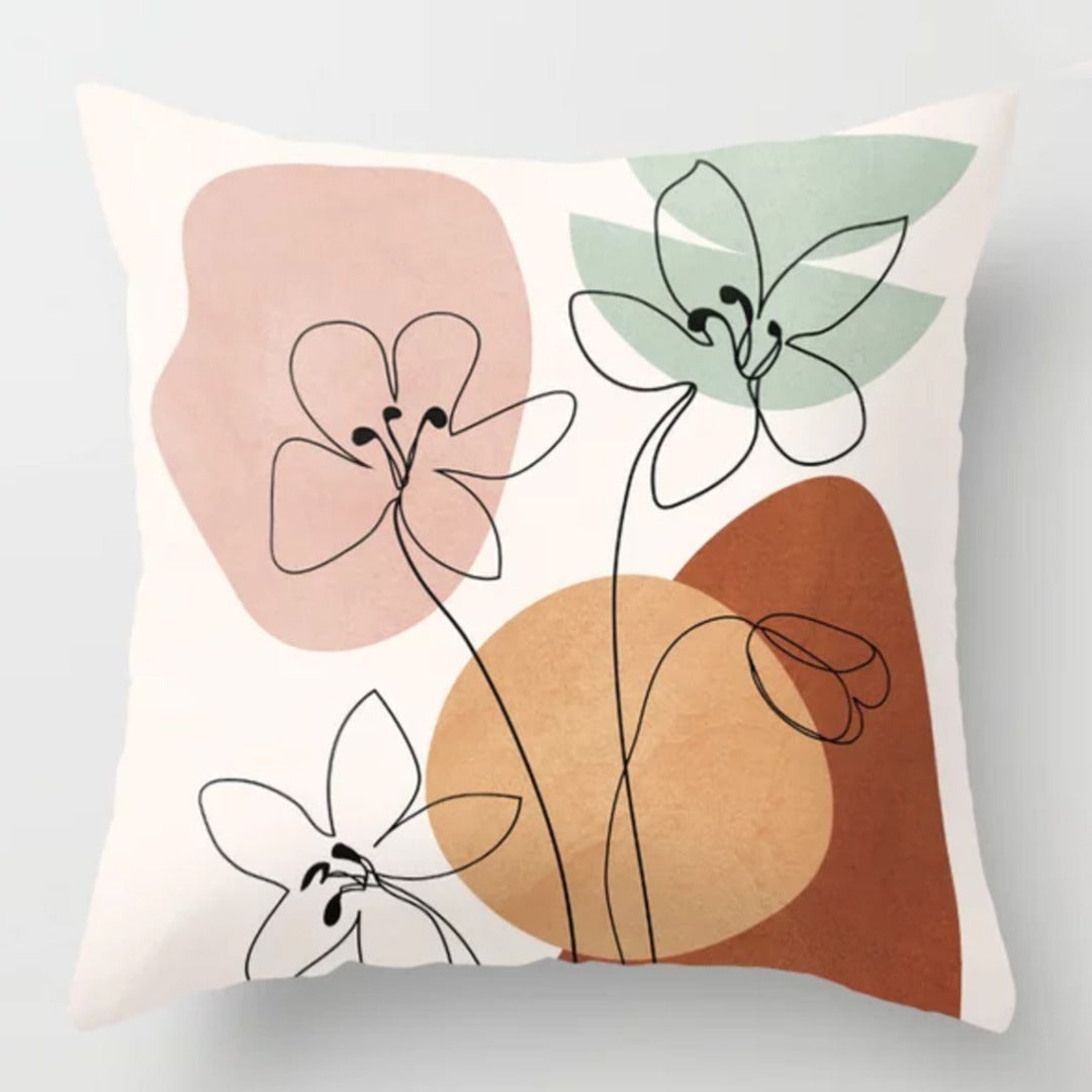 Cream cushion cover with fine floral outlines over pink, green and rust shapes.