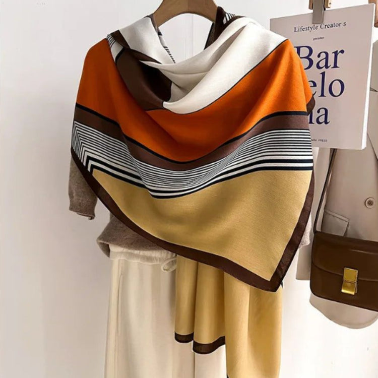 Close-up of a colour-block scarf with orange and tan panels and black striped borders.