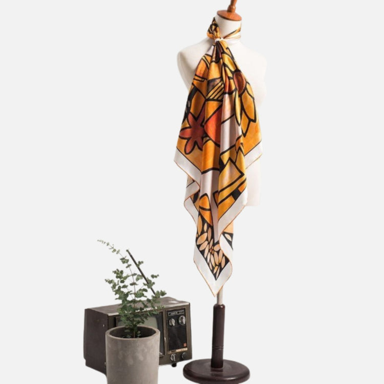 Orange, yellow and black floral scarf displayed on a stand.