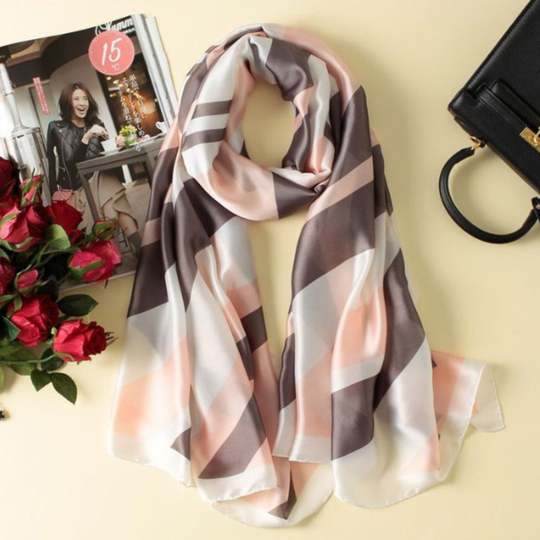 Soft pink, grey and cream geometric scarf arranged beside accessories.
