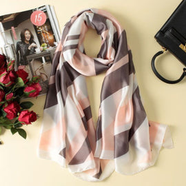 Soft pink, grey and cream geometric scarf arranged beside accessories.