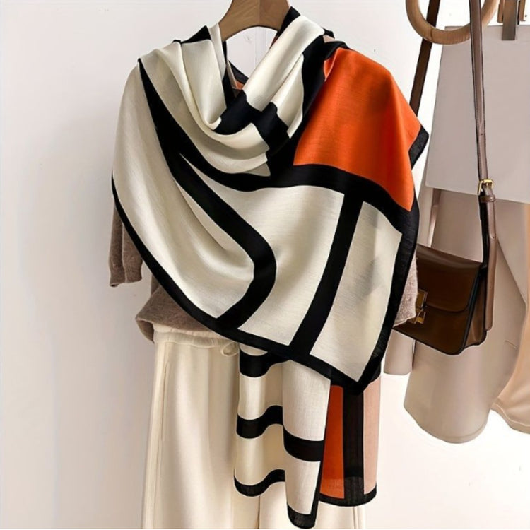 Cream, black and orange scarf draped on a stand.
