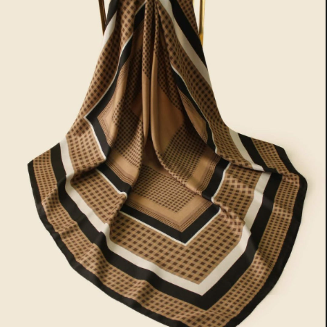 Brown and black geometric striped scarf draped on a wooden hanger.