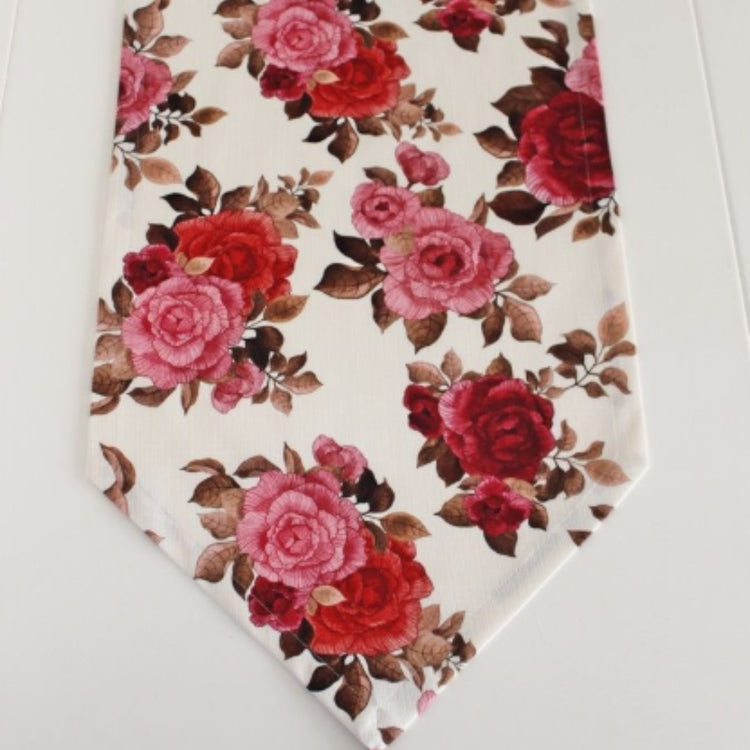 Close-up of red and pink roses on a cream table runner.