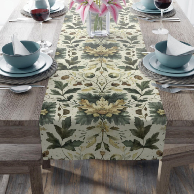 Cream table runner with green foliage and golden floral motifs on a set table.