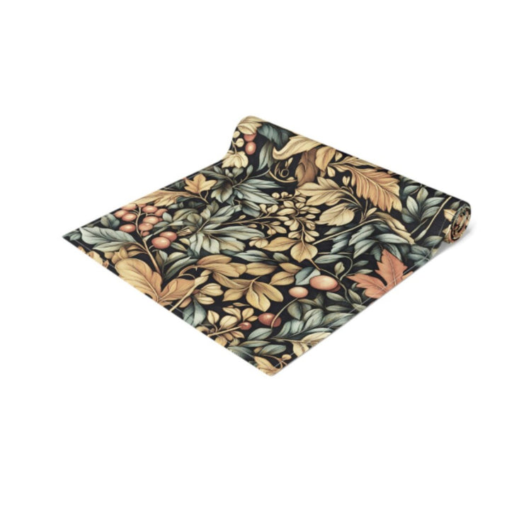 Folded dark botanical table runner with gold, green and orange leaf motifs.