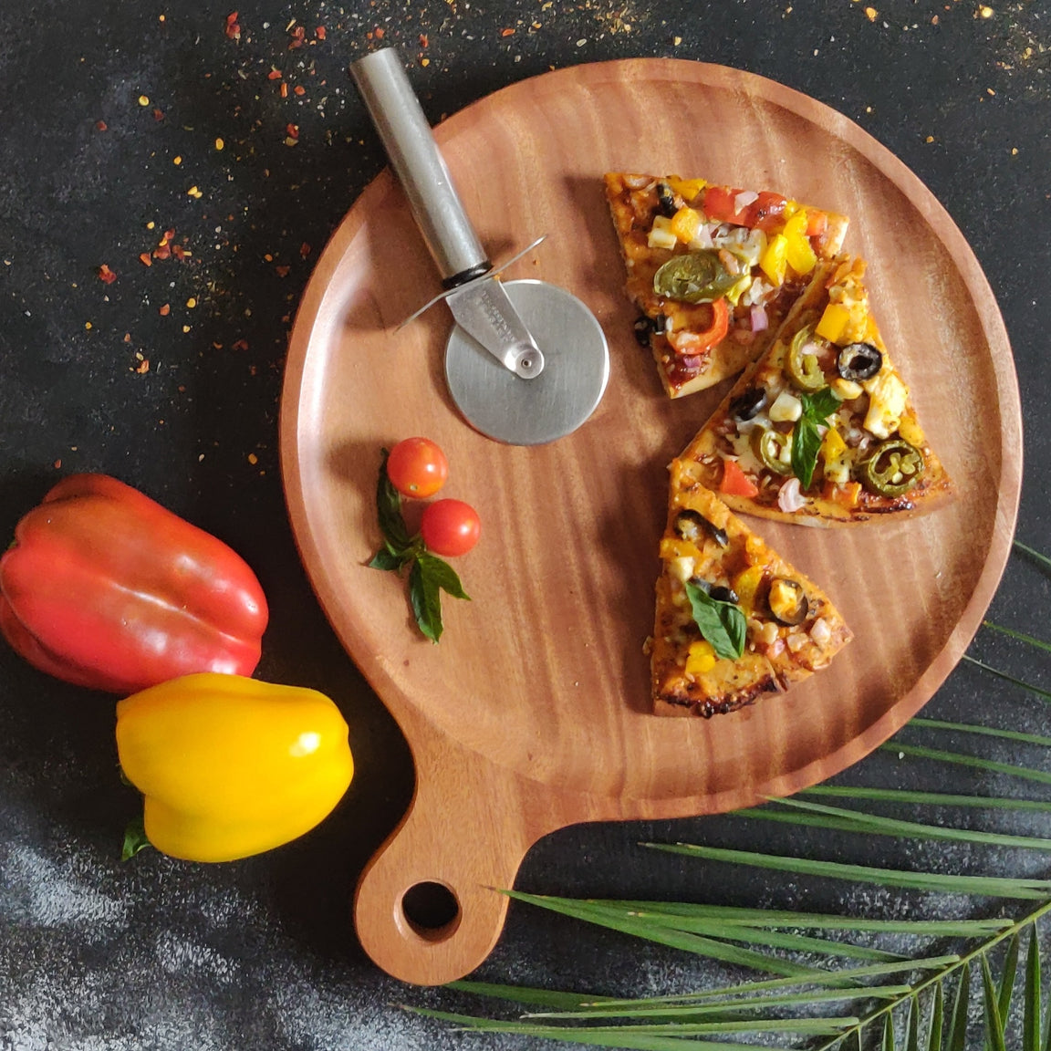Round wooden serving board with handle, shown with pizza slices and a pizza cutter.