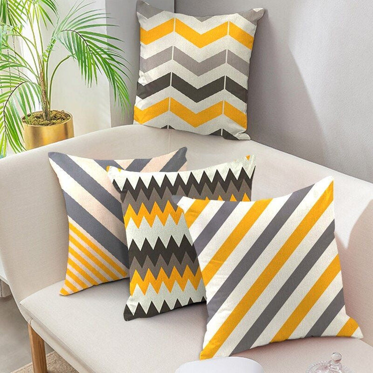 Four mustard, grey and white cushion covers with chevrons, triangles and diagonal stripes.