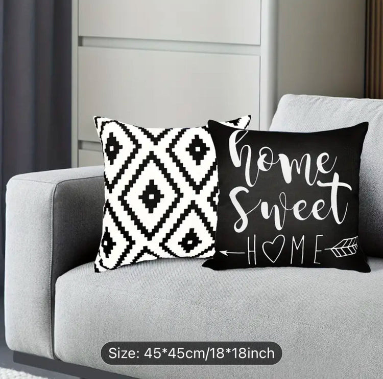 Black and cream diamond and Home Sweet Home cushion covers together on a sofa.