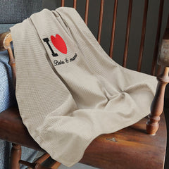 Beige blanket with 'I love Babs & Momo' embroidery on a wooden chair.