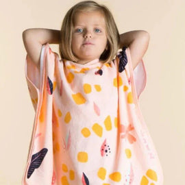 Child wearing a peach giraffe-pattern hooded towel poncho.