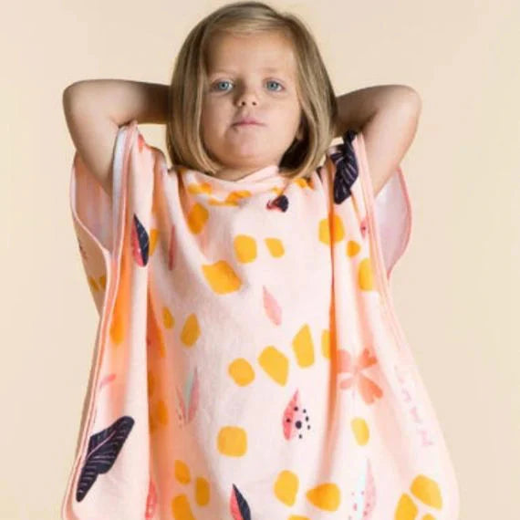 Child wearing a peach giraffe-pattern hooded towel poncho.