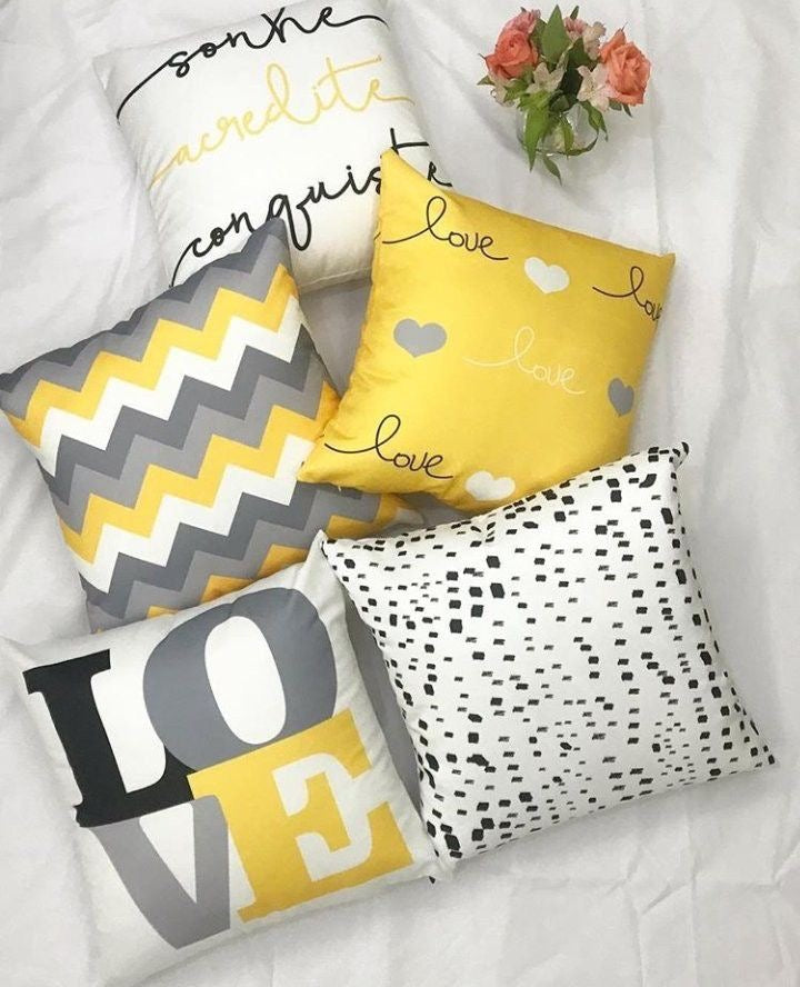 Five yellow, grey, black and white cushion covers with LOVE lettering and mixed graphic patterns.