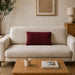 Rectangular burgundy filled cushion with angular stitched lines on a cream sofa.
