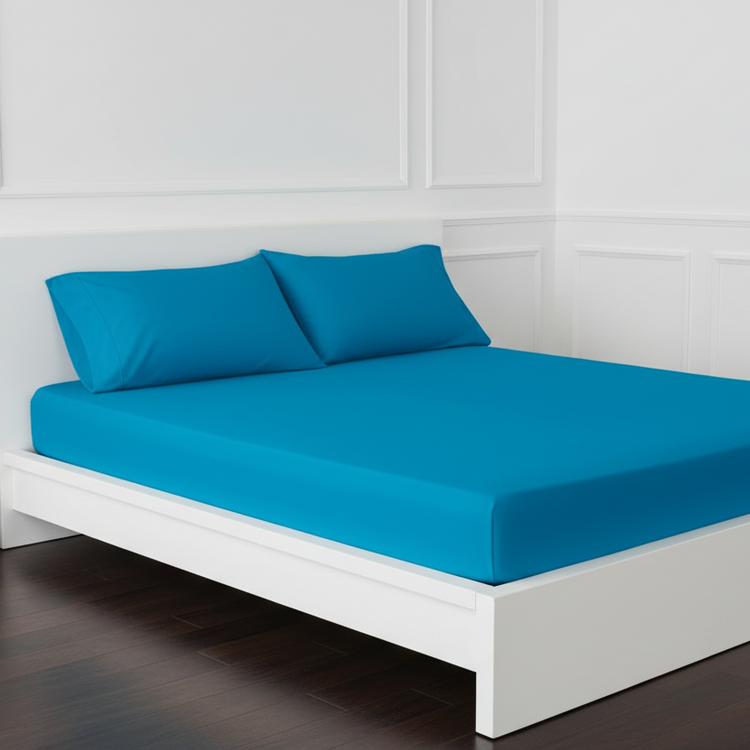 Teal cotton fitted sheet displayed on a double bed with matching pillowcases.