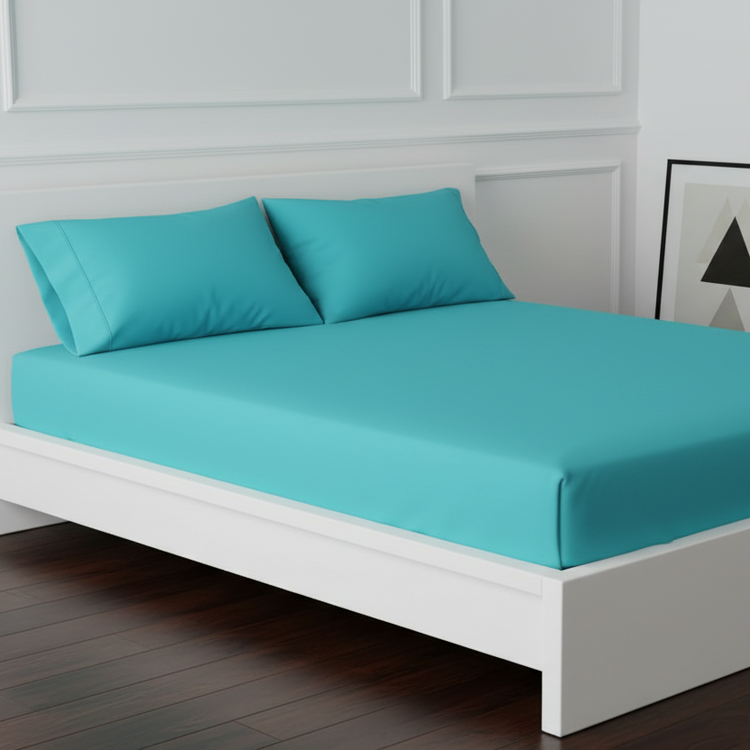 Peacock blue fitted sheet and matching pillowcases displayed on a bed.