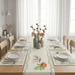 Cream botanical table runner with coordinating placemats on a dining table.