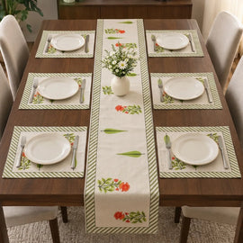Wooden dining table styled with white plates and gold cutlery, featuring a cream-colored runner with alternating green leaves and orange floral motifs, framed by green diagonal-striped borders.   with 6 mats 