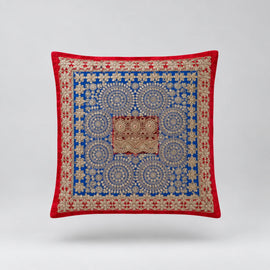 Red-bordered cushion cover with a dense blue ornamental pattern and small brown central panel.
