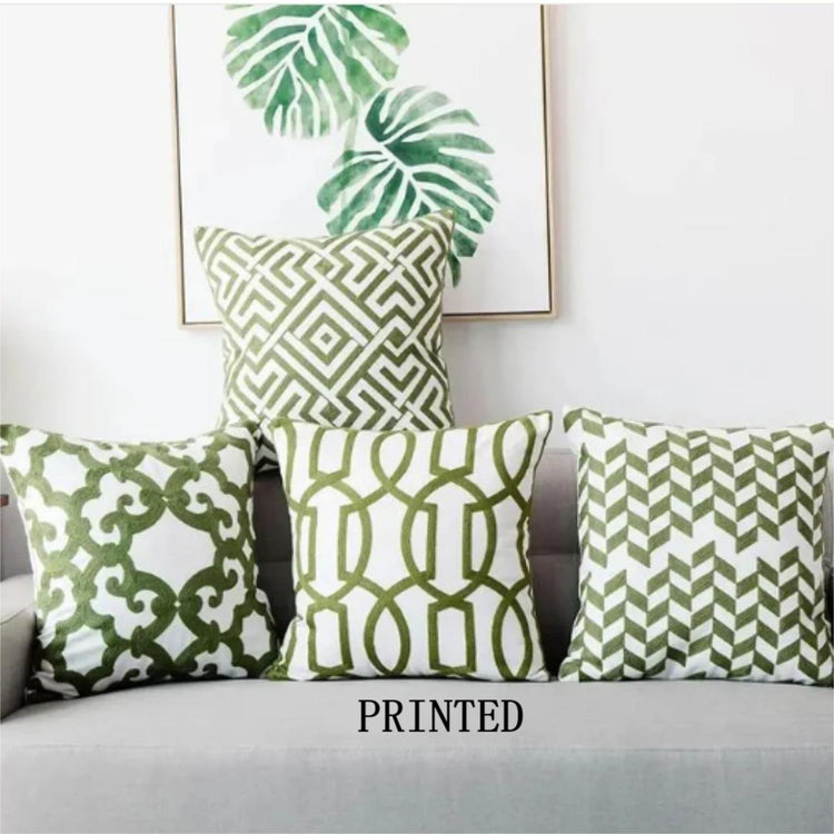 Four green and cream cushion covers with printed geometric patterns on a sofa.