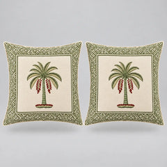 Two square decorative throw pillows shown side by side on a light gray background. Each pillow has an off-white center panel featuring a green palm tree with red hanging fruit, surrounded by a green geometric border.