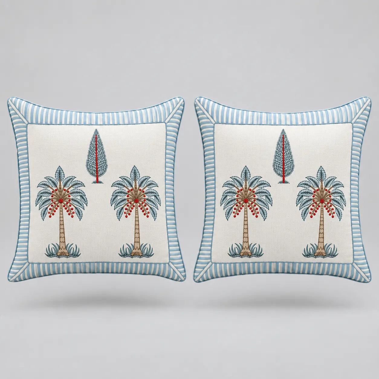 Two square decorative throw pillows with a light blue and white striped border, featuring a central cream-colored panel with embroidered palm trees and a small tree motif.