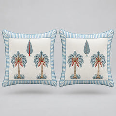 Two square decorative throw pillows with a light blue and white striped border, featuring a central cream-colored panel with embroidered palm trees and a small tree motif.