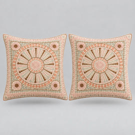 Two square decorative throw pillows with intricate circular medallion embroidery in dusty pink, beige, and brown, set against a solid light gray background.