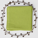 Folded light green baby blanket with a waffle texture and plain border, surrounded by decorative berry branches.