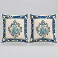 Two square decorative throw pillows with intricate blue and gold traditional patterns on a cream background, set against a neutral gray studio backdrop.