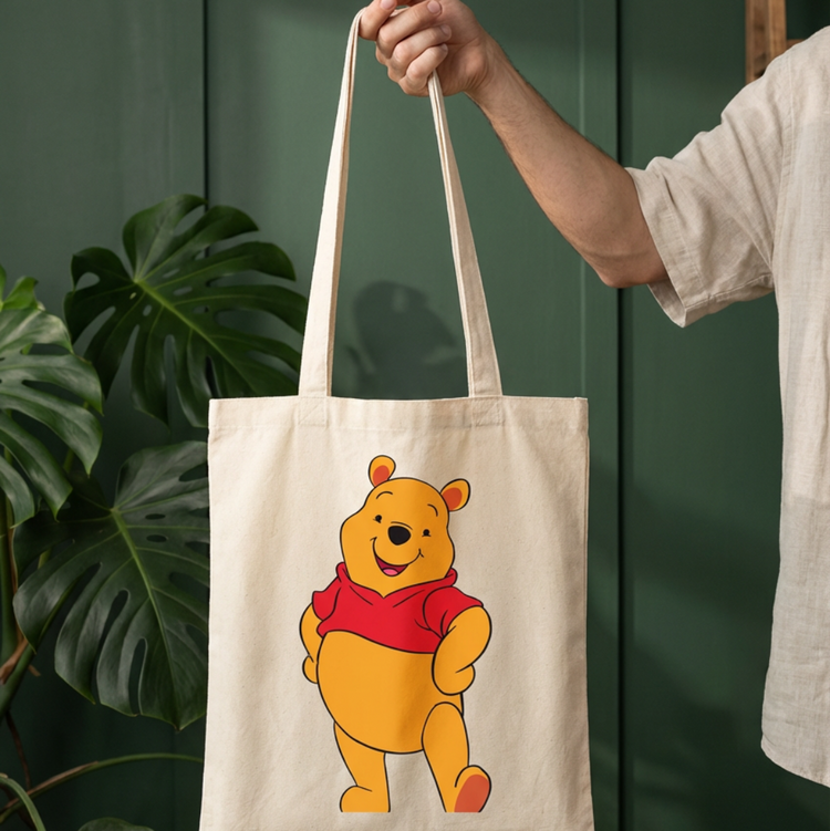 Cream tote bag with a yellow cartoon bear wearing a red shirt.