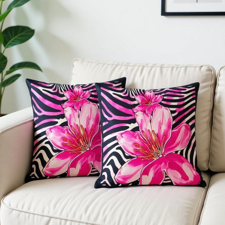 Two black and white striped cushion covers with large pink flowers on a sofa.