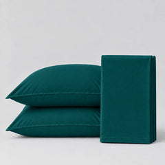 A set of dark teal bedding, including two pillows and a folded sheet or pillowcase, displayed on a clean light gray background.