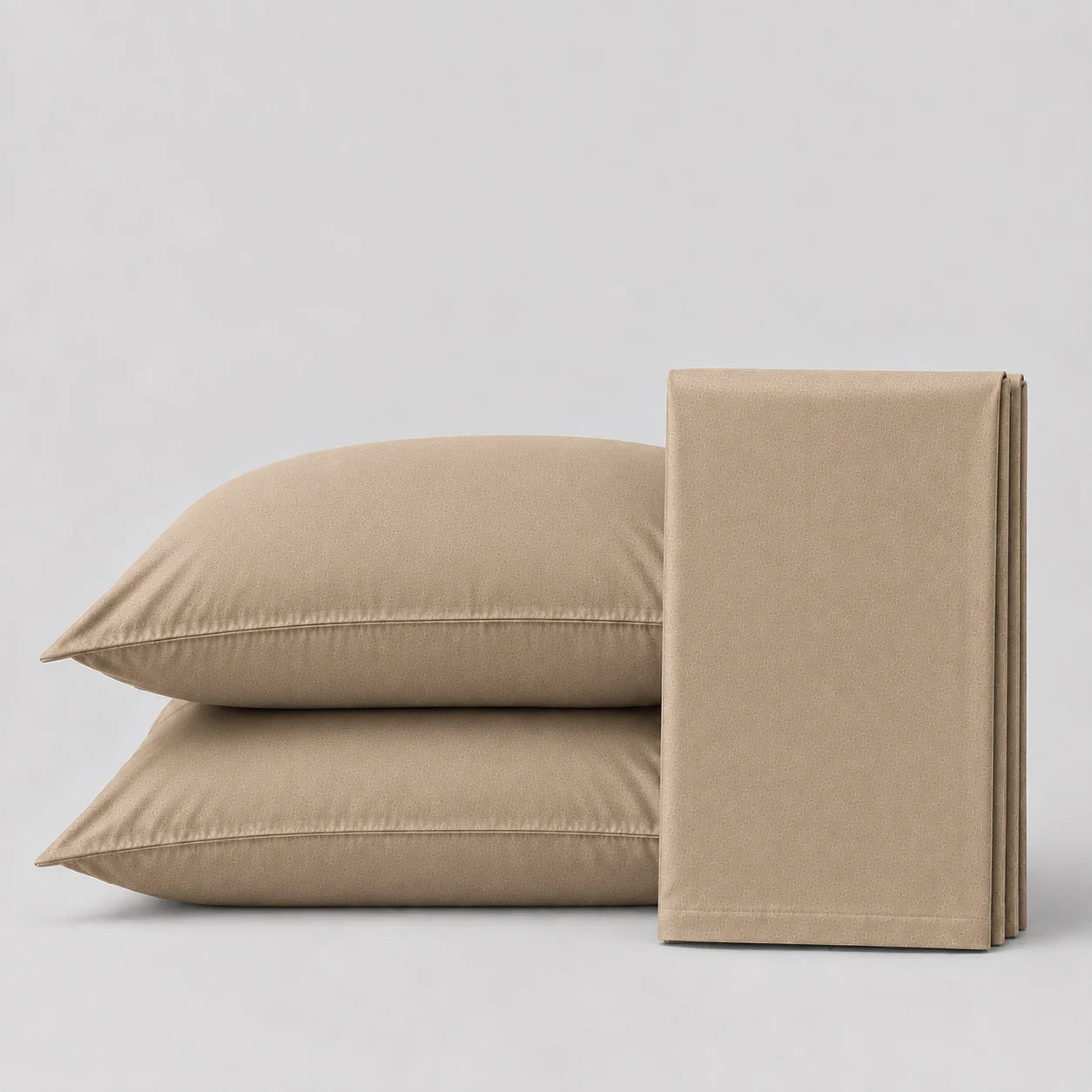 Light tan  bedsheet and pillows  on a light grey surface 