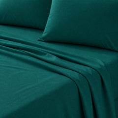 Dark teal green bed sheet set with matching pillowcases, shown with soft folds on a bed.