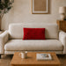Rectangular red filled cushion with angular stitched lines on a cream sofa.