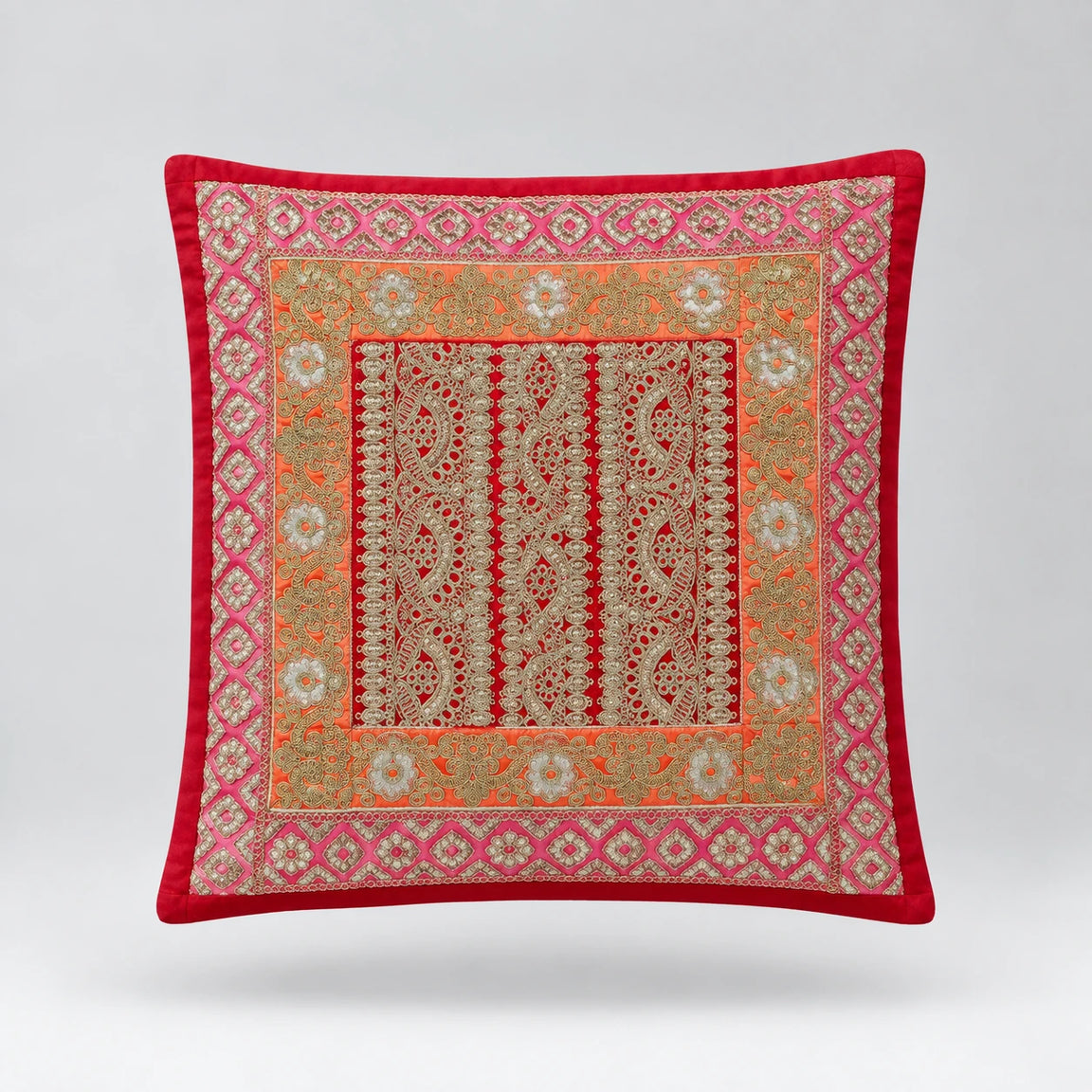 Red cushion cover with delicate pale ornamental borders and narrow patterned central panels.