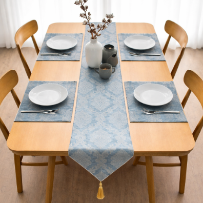 Blue ornamental table runner and matching placemats beneath white tableware.