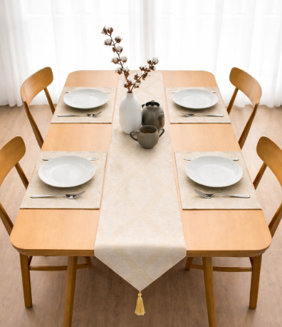Pale gold patterned table runner with matching placemats on a set dining table.