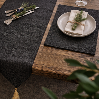 Close view of a black textured runner and matching placemat beneath a plate.