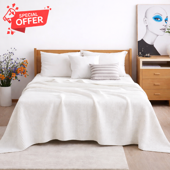 White cotton thermal blanket draped over a bed.