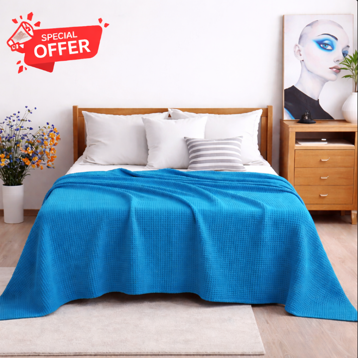 Turquoise cotton thermal blanket draped over a bed.